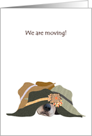 We are moving, dog asleep under a pile of hats, new address card