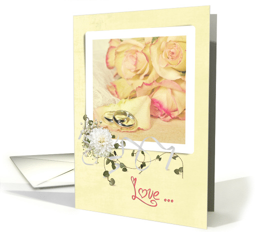 wedding anniversary rings on rose petal with bouquet on frame card